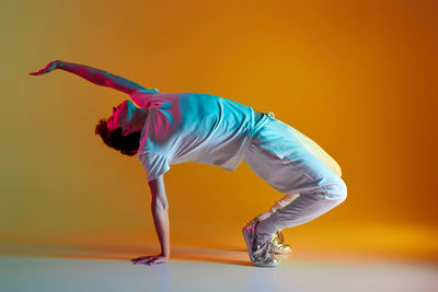 Full length of young woman exercising against blue background