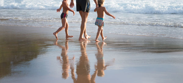 Low section of women walking on beach