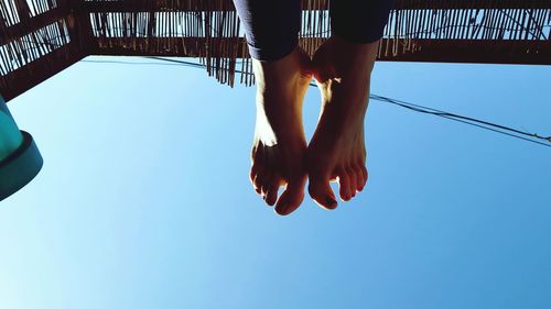 Low section of woman legs against clear blue sky