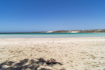 Slippers at beach against sky