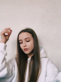 Beautiful young woman with eyes closed against wall