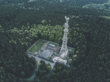 Aerial: drone shot of old abandones radio tower station in rich green forest surrounded by trees