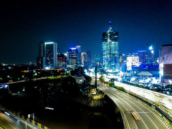 City street amidst illuminated buildings against sky at night