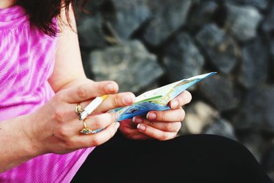 Midsection of woman holding cigarette and paper outdoors