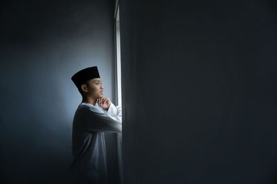 Portrait of young man standing against black background