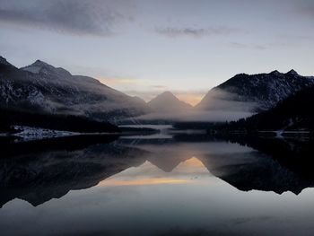 Scenic view of lake by mountains against sky during sunset