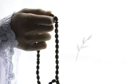 Close-up of hand holding cross against white background