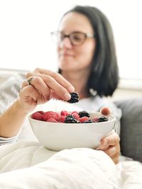 Mature woman eating fruits while sitting on sofa at home