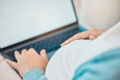 Cropped hand of woman using laptop