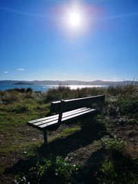 Empty bench on landscape against bright sun