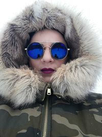 Portrait of woman wearing blue sunglasses and fur coat
