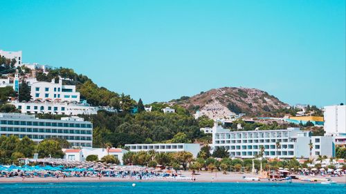 Scenic view of sea by buildings against clear sky