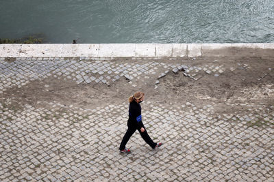 High angle view of woman walking on footpath by sea