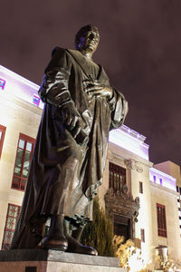 Low angle view of statue against city at night
