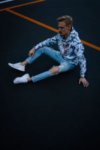 High angle view of young man sitting on basketball court