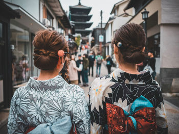 Rear view of women walking on street in city