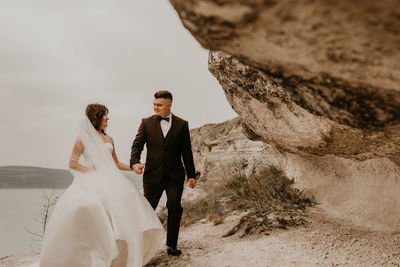 Rear view of bride and bridegroom standing on rock