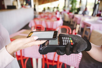 Mature woman paying bill through mobile phone while standing at restaurant