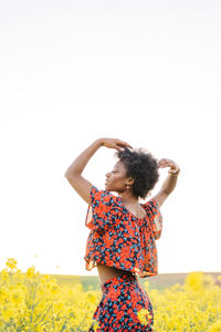 Rear view of woman standing on field against clear sky