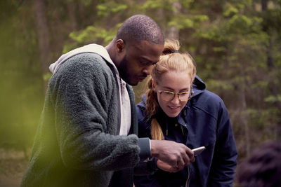 Man showing smart phone while standing in forest