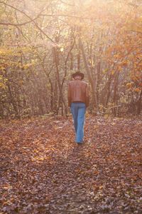 Rear view of boy in forest during autumn