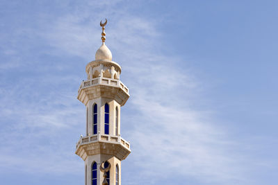 Minaret of the mosque against blue sky with wispy clouds in abu dhabi, uae