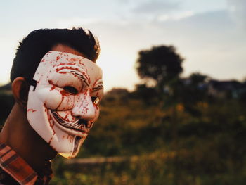 Close-up of man wearing mask during sunset