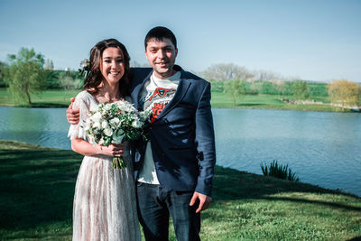 Portrait of smiling young couple standing by lake