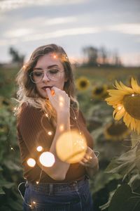 Young woman with string lights standing in field during sunset