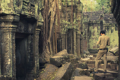 Rear view of guide standing at old ruin ankor wat temple