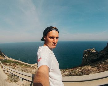 Portrait of young man standing on mountain against sea