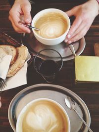 Close-up of hand holding coffee cup on table