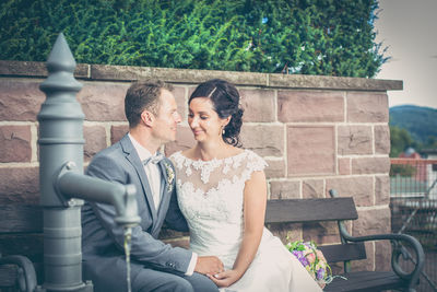 Smiling bride and groom sitting on bench