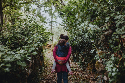 Rear view of woman standing amidst plants in forest