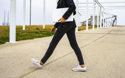 Woman walking and carrying a white laptop.