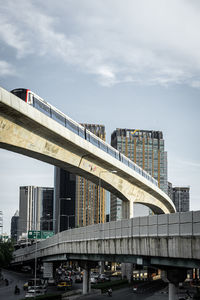 Low angle view of elevated road by buildings against sky