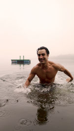 Shirtless man standing in lake