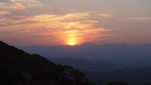 Scenic view of silhouette mountains against orange sky