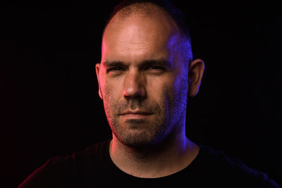 Portrait of young man against black background