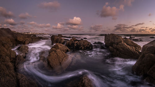 Rocks at sea against sky during sunset