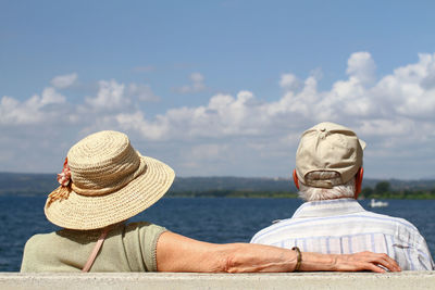 Elderly couple sitting on a bench by the lake.