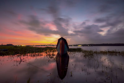 Cropped image of man standing by lake against sky during sunset