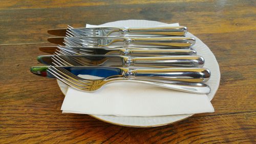 Close-up of neatly arranged cutlery on wooden table