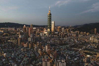 Illuminated buildings in city against sky