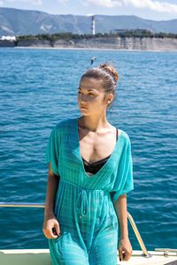 Young woman looking away while standing in boat at sea