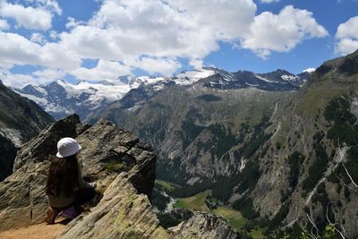 Full length of girl crouching while looking at mountain against sky