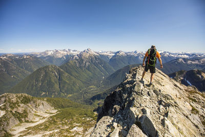 Rear view of backpacker hiking on mountain summit ridge with view.