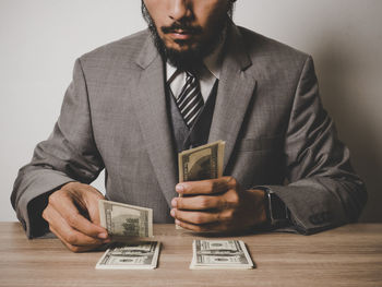 Midsection of businessman with paper currency at table