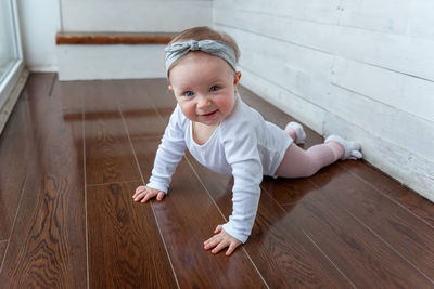 Portrait of cute boy sitting on hardwood floor at home