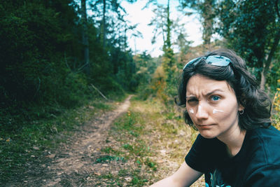 Portrait of a blue-eyed girl looking at camera and making fun with sunscreen on her face in nature